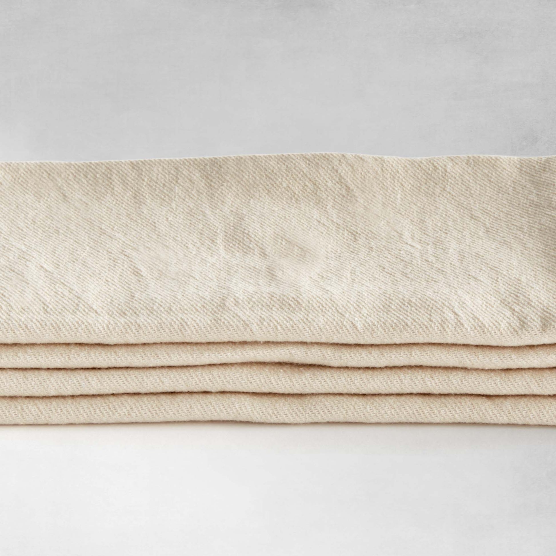 Tan square cotton dinner napkins, set of 4, stacked on top of each other, side view closeup.