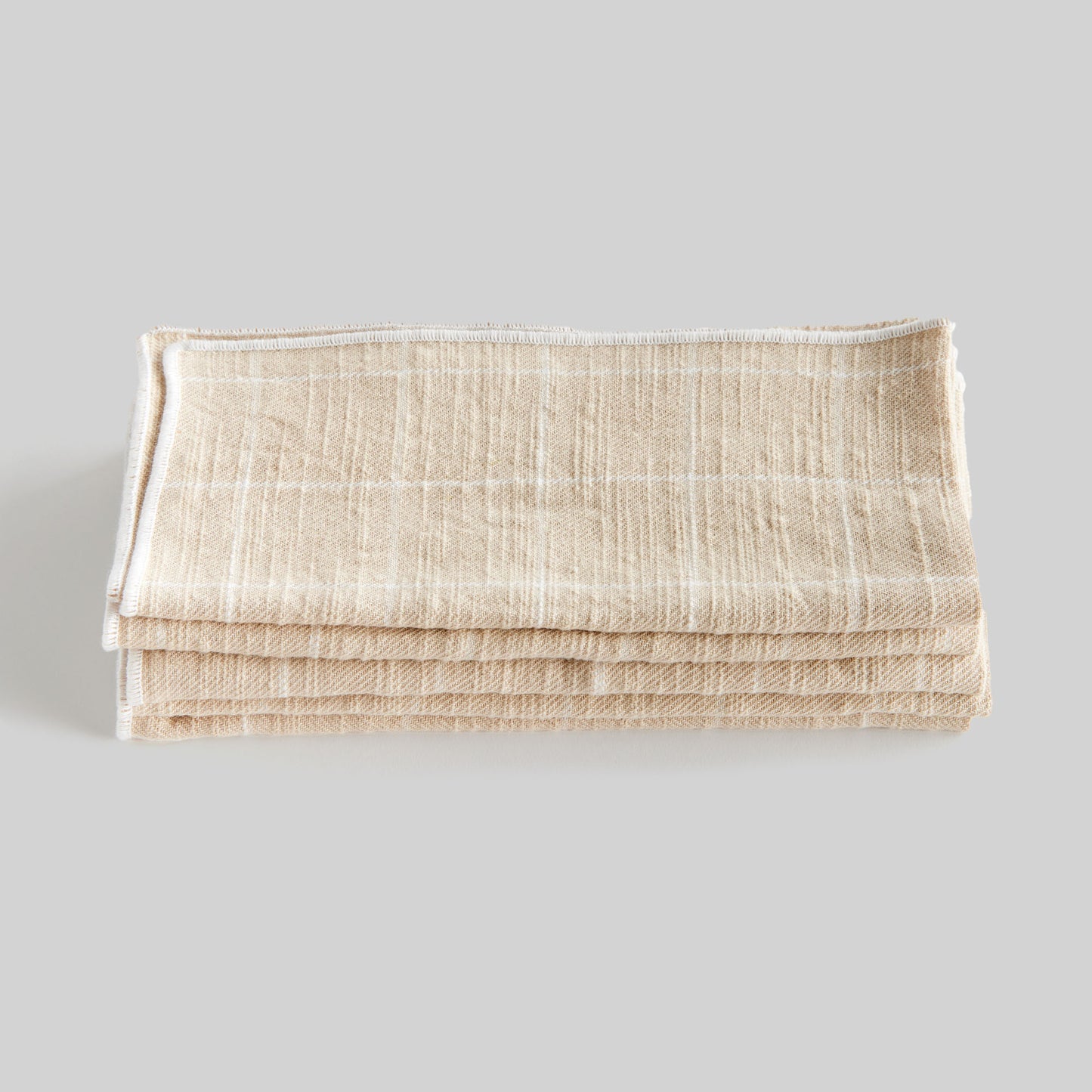 Tan windowpane square cotton dinner napkins set of 4, stacked and folded, with gray background.