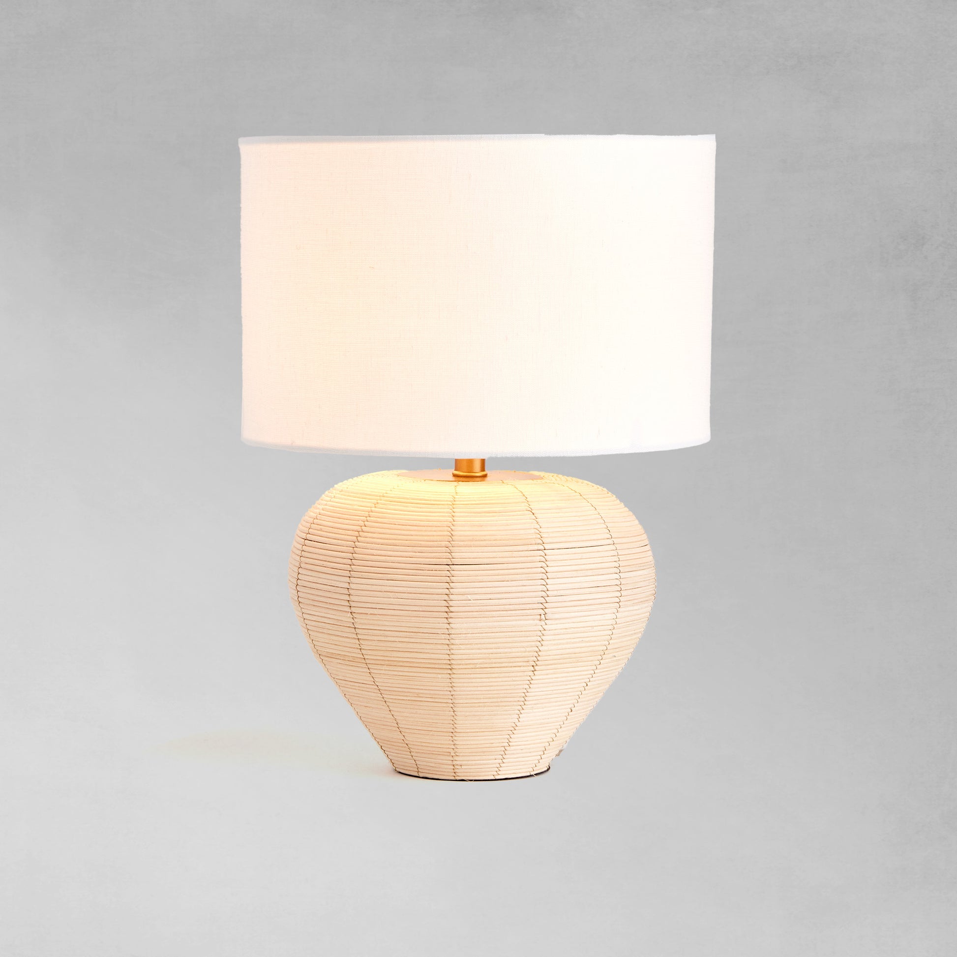 Tapered rattan mini lamp, illuminated, with gray background.