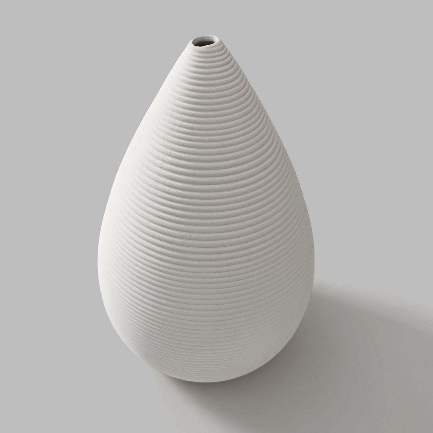 White ceramic vase with ribbed texture on a gray background