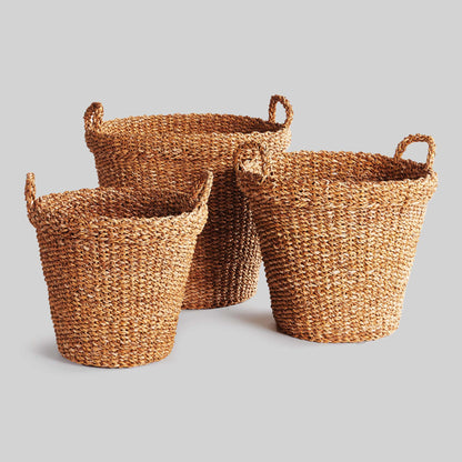 Tapered woven seagrass baskets with gray background.