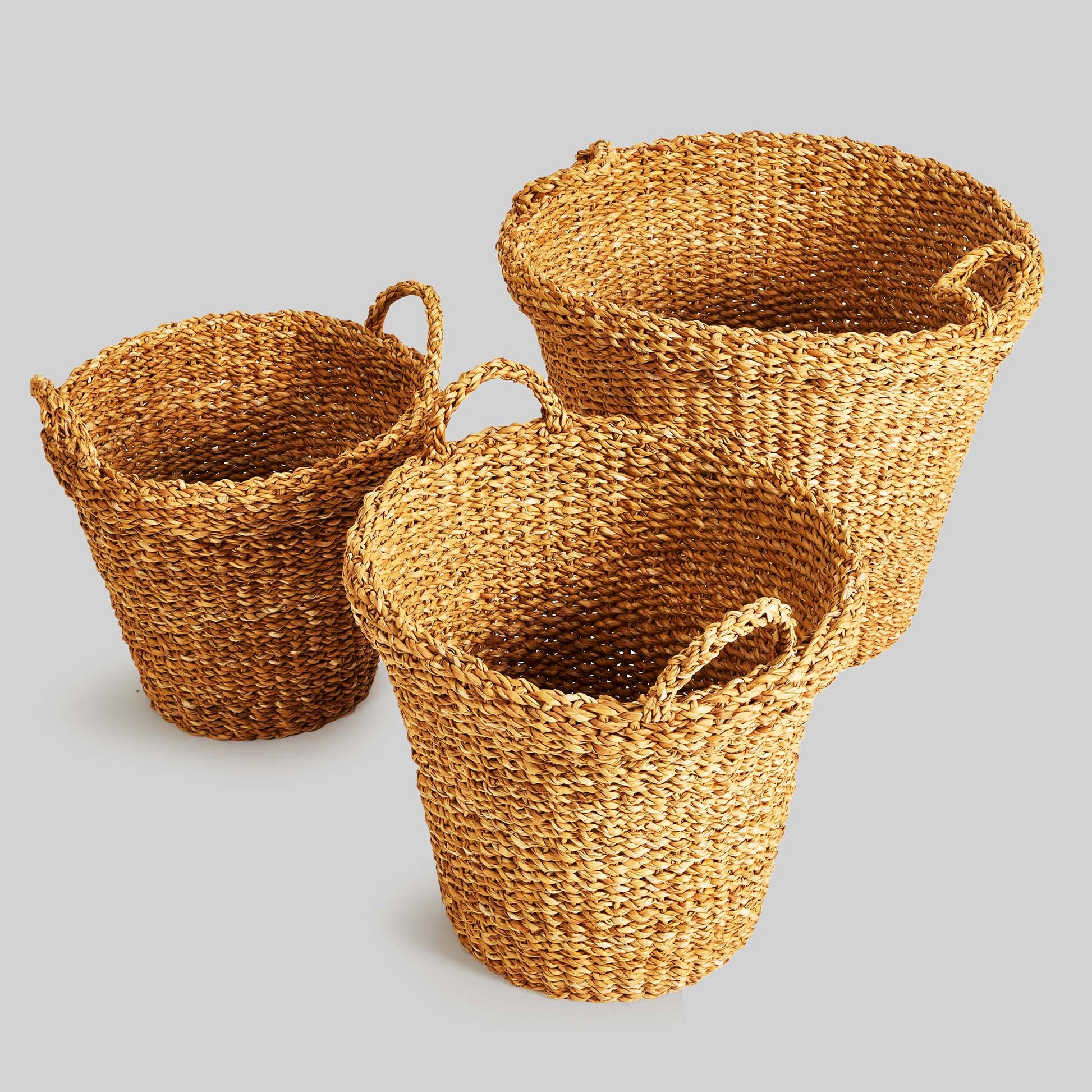 Tapered woven seagrass baskets, top view, with gray background.