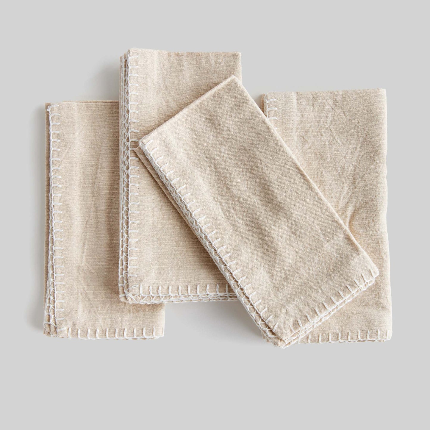 Taupe whipstitch square cotton dinner napkins set of 4 with gray background.