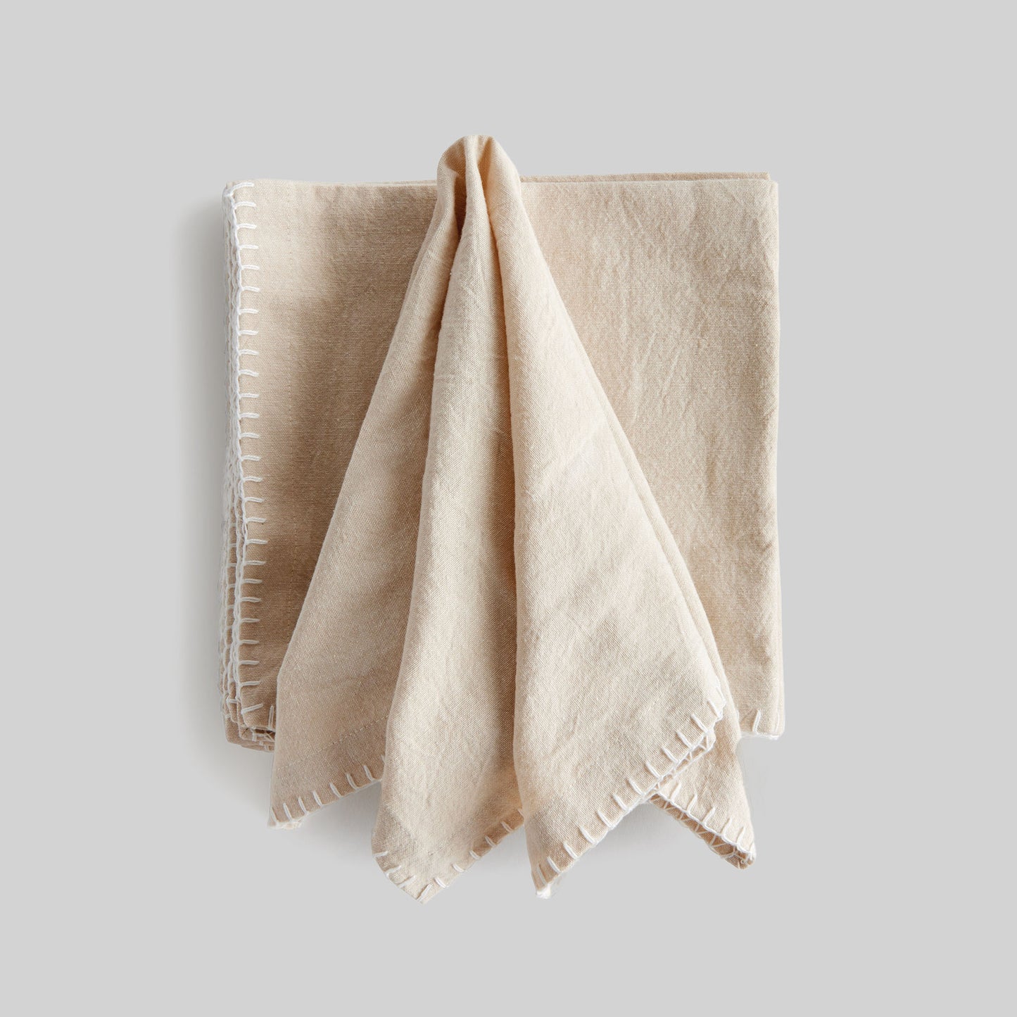 Taupe whipstitch square cotton dinner napkins set of 4, unfolded, with gray background.