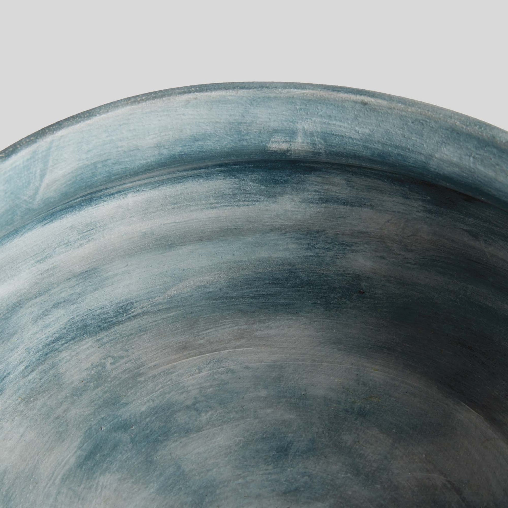 Weathered blue-gray terracotta decorative bowl, closeup view, with gray background.