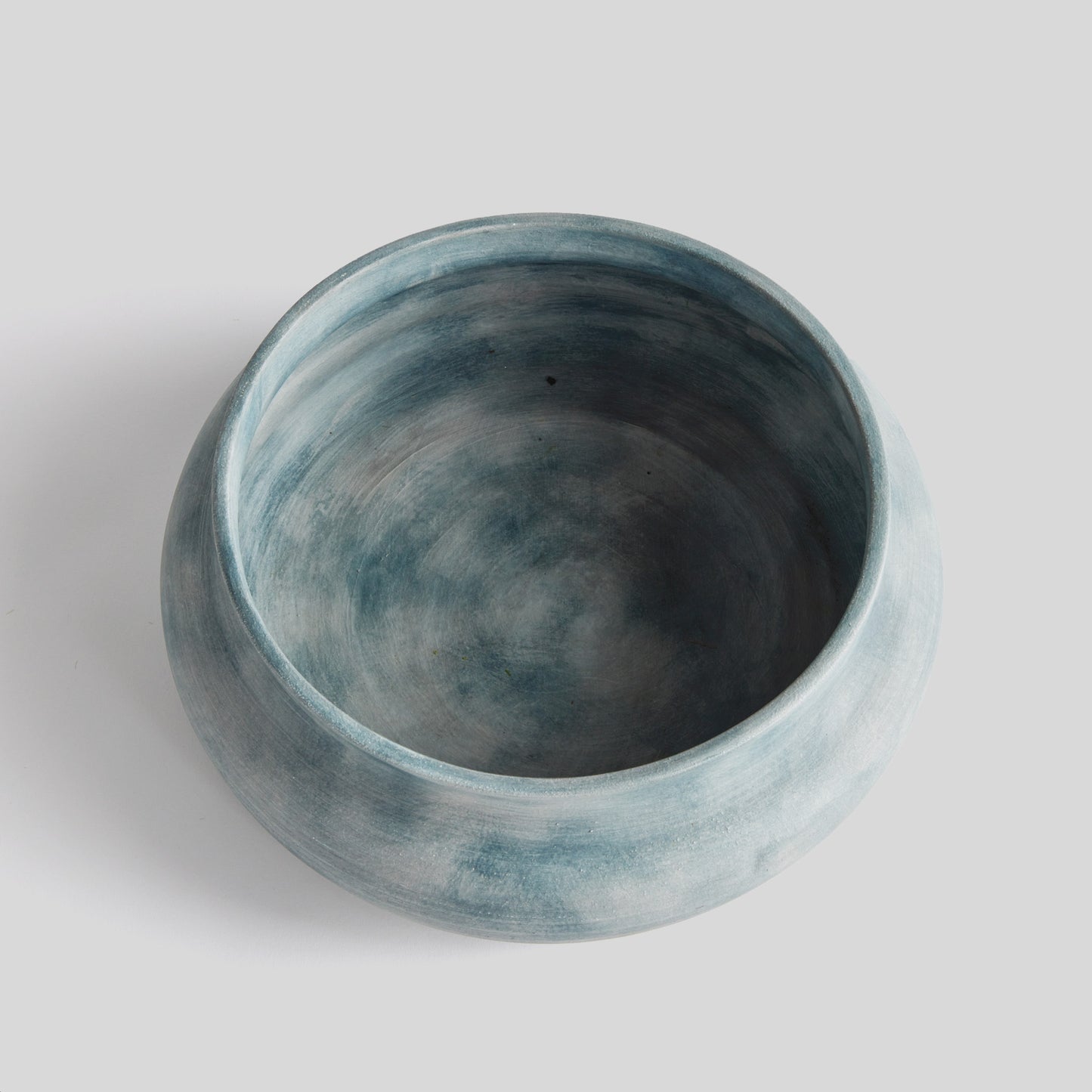 Weathered blue-gray terracotta decorative bowl, top view, with gray background.