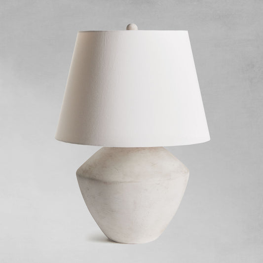 Weathered gray round ceramic table lamp with gray background.