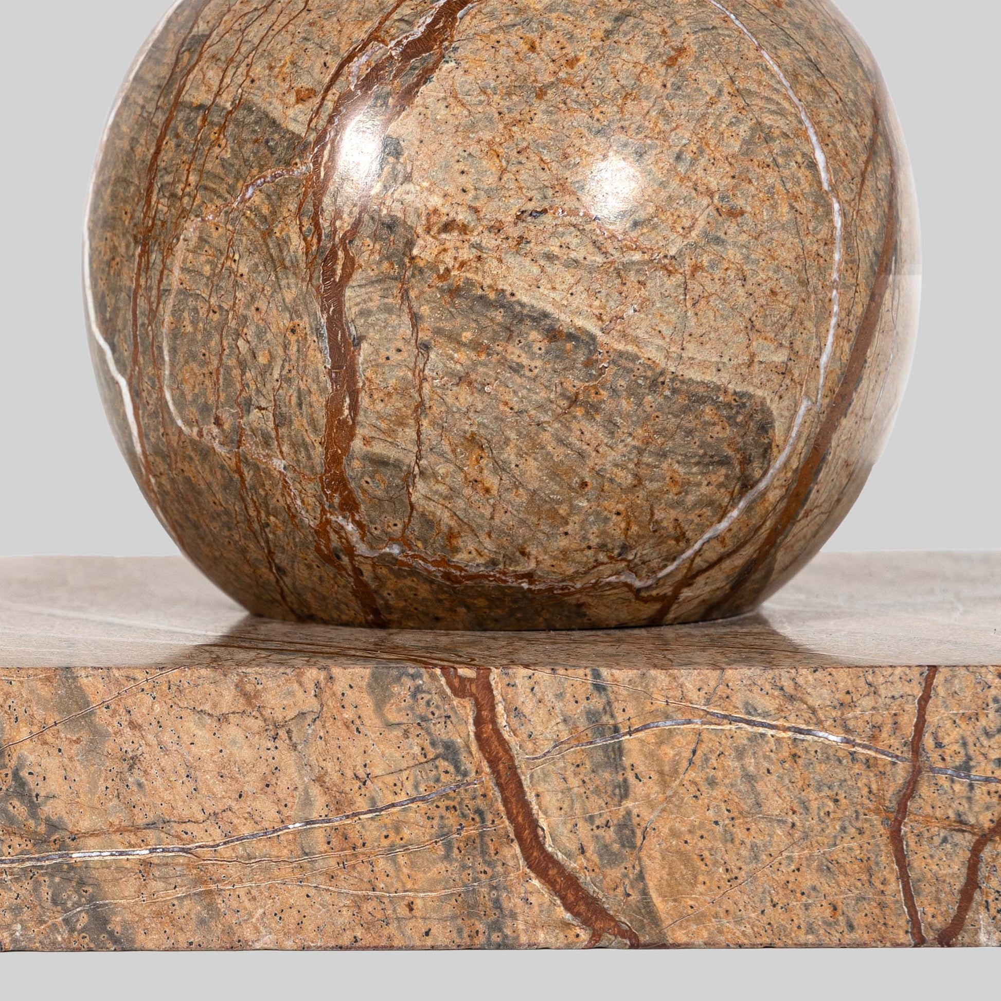 Small round cocktail table with marble top and brass base on a light gray background.