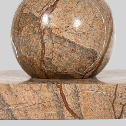 Small round cocktail table with marble top and brass base on a light gray background.
