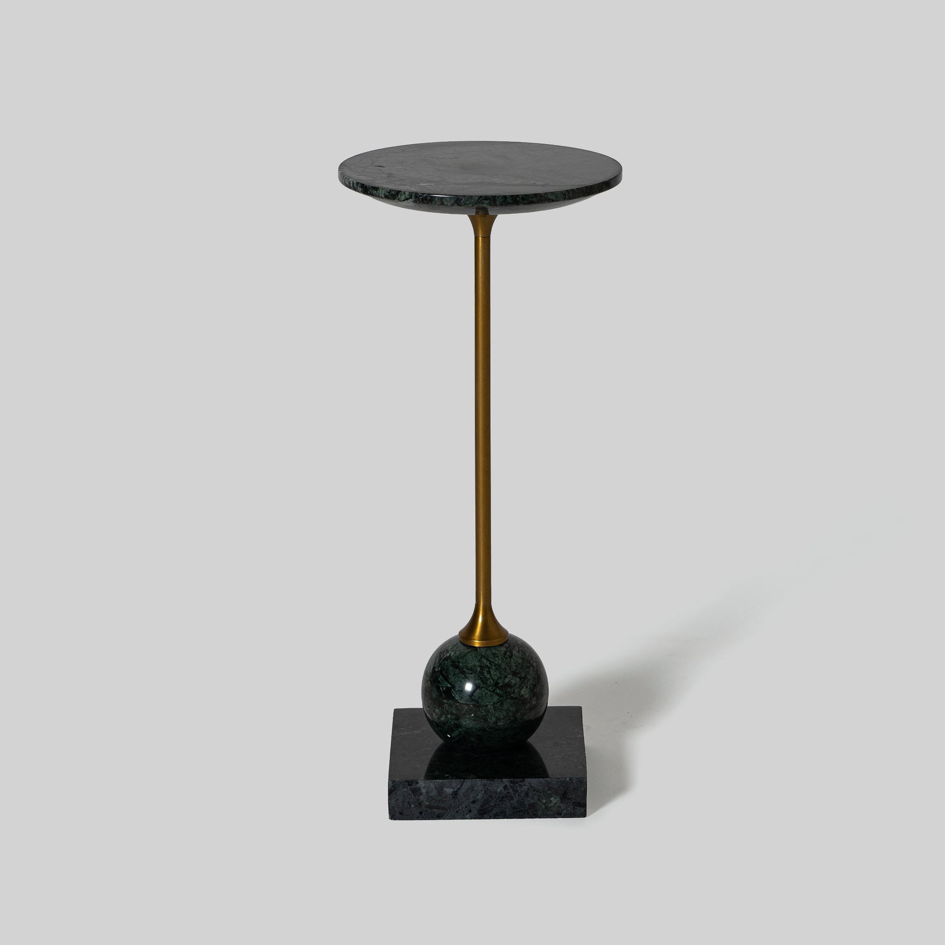 Small round cocktail table with marble top and brass base on a light gray background.