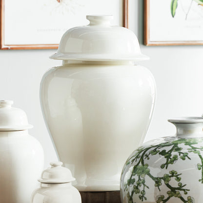 White ceramic lidded ginger jar, large, stylized on table with other ginger jars.