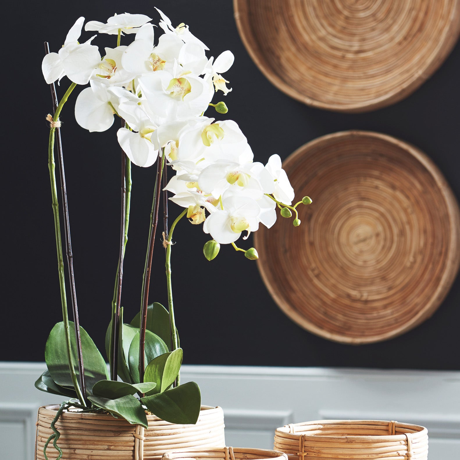 White orchid faux floral drop-in, 30", stylized on table with rattan cane cachepot.