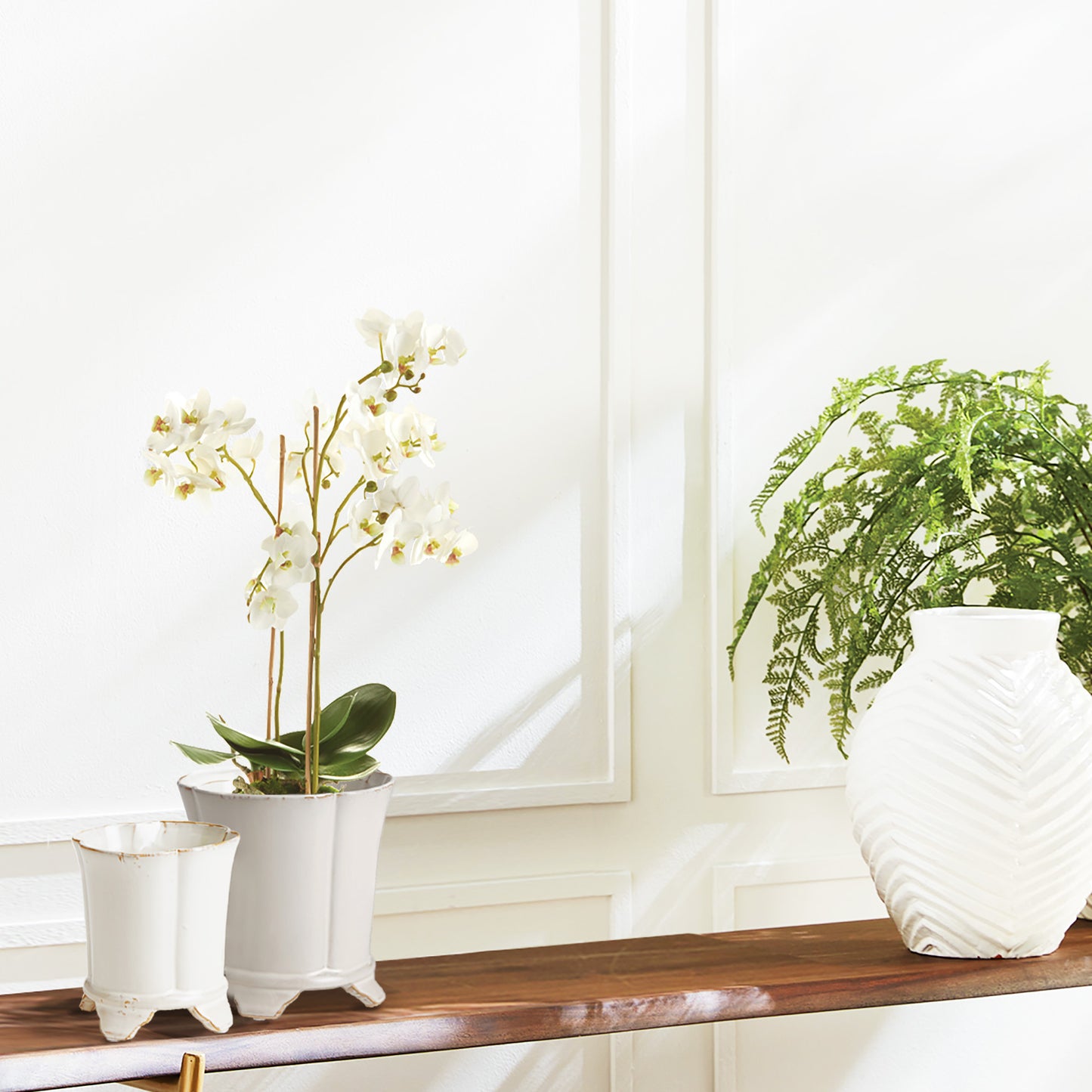 White orchid faux floral drop-in stylized in cachepot on console table.