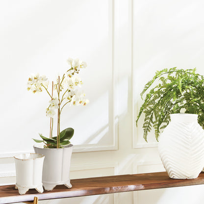 White orchid faux floral drop-in stylized in cachepot on console table.