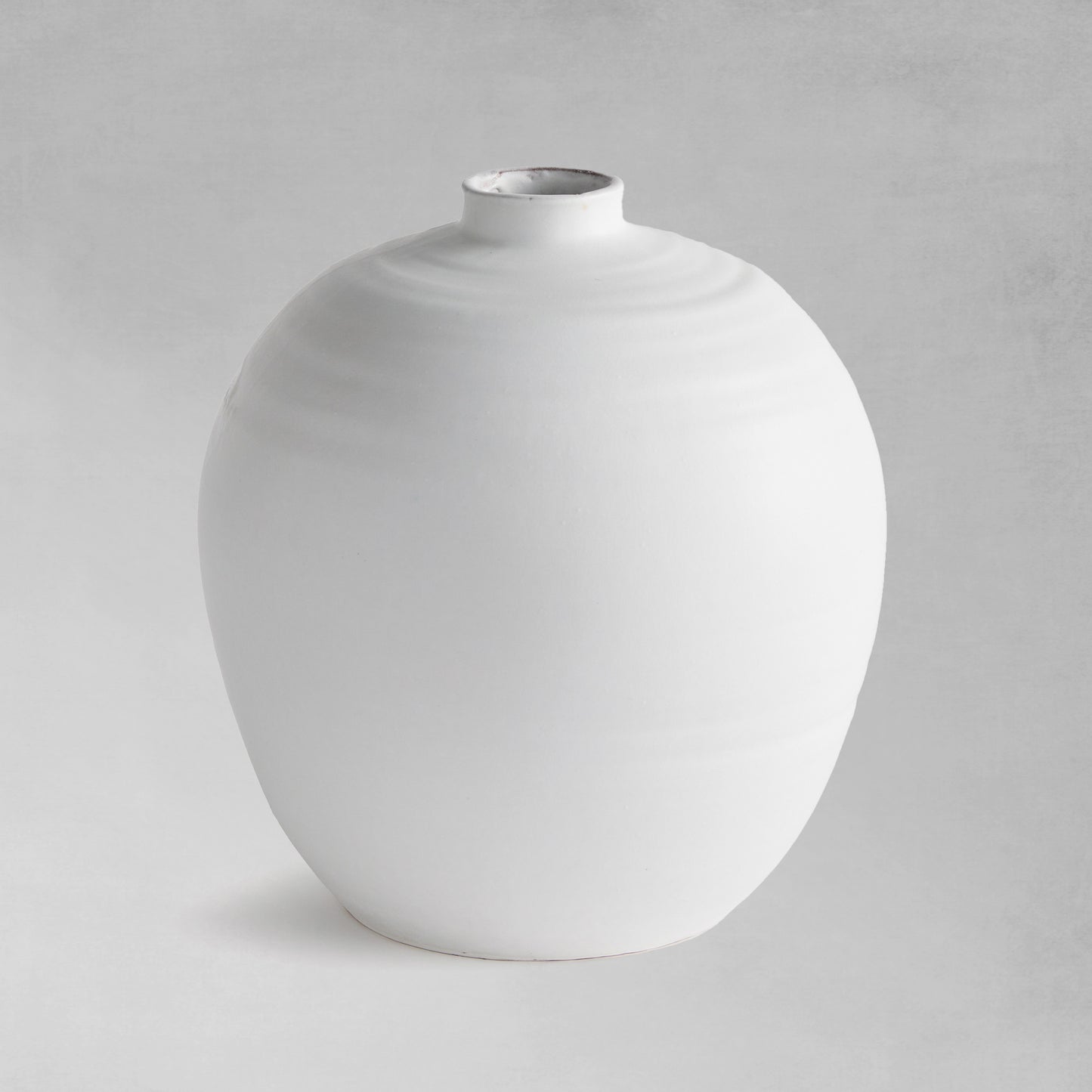 White terracotta vase with matte glaze on a gray background.