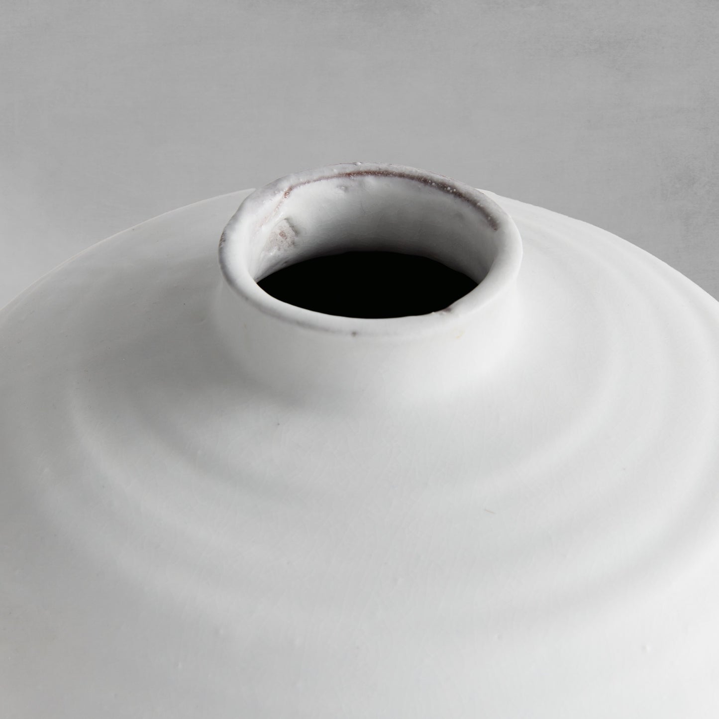 Close-up top view of a white terracotta vase with matte glaze.