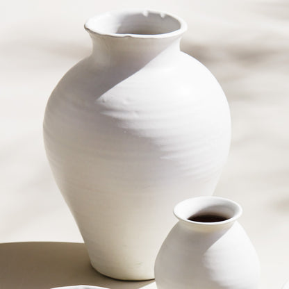 White terracotta wide-mouth vases, large, stylized on a table.