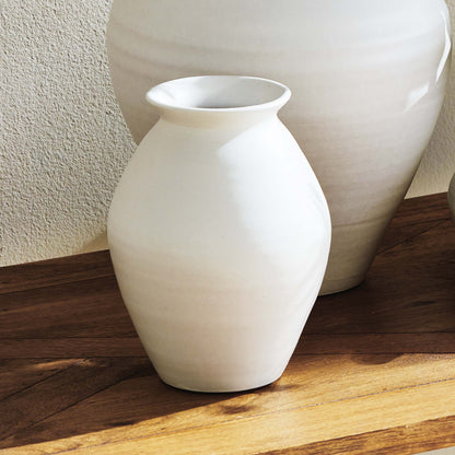 White terracotta wide-mouth vases, small, on a wooden table.