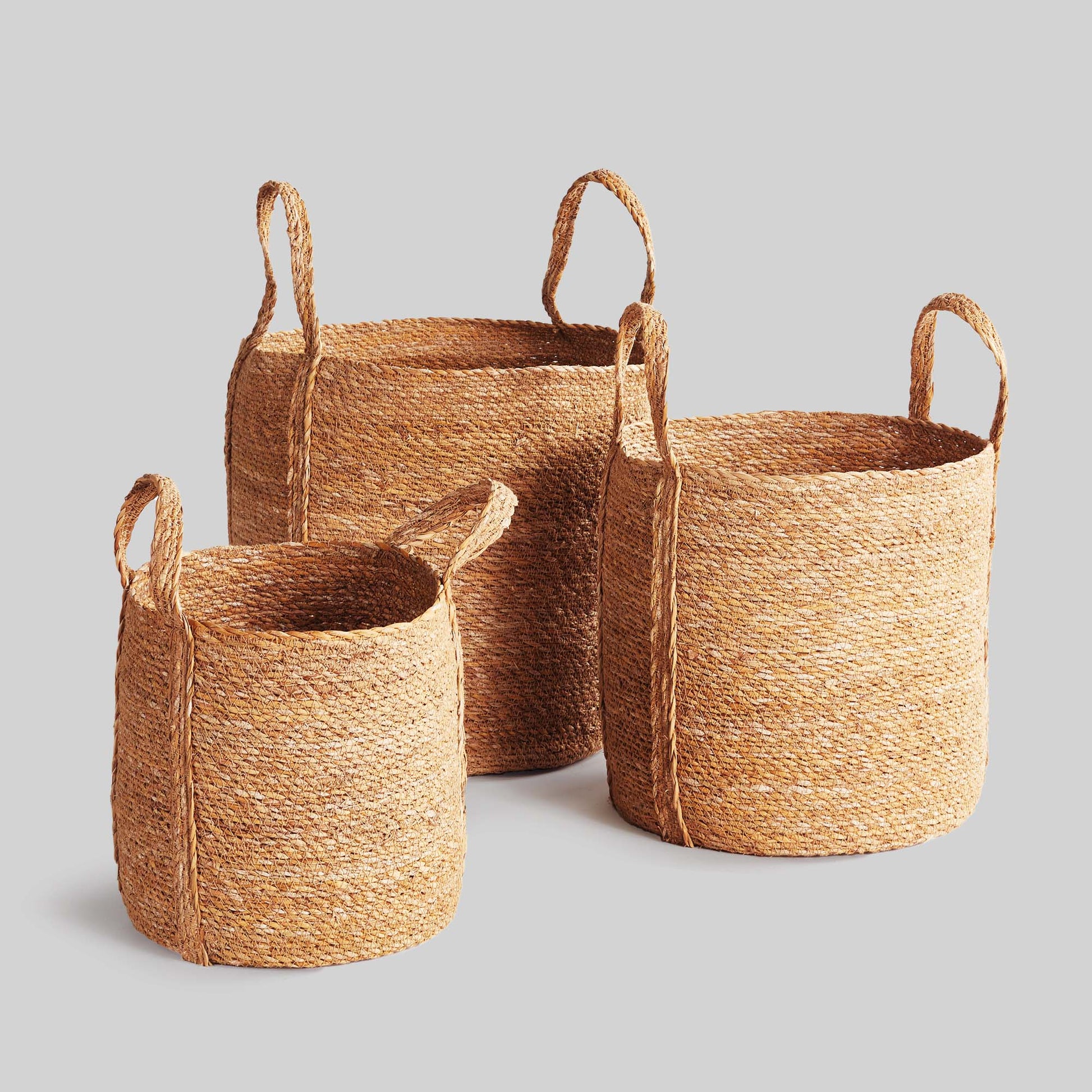 Woven seagrass round baskets with gray background.