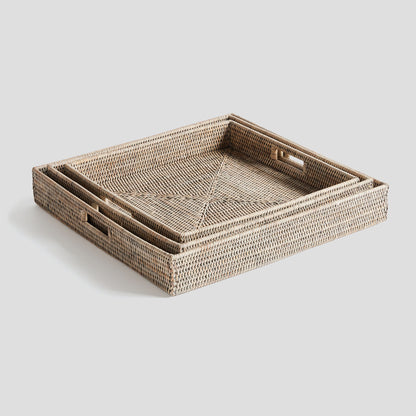Woven square ottoman tray set in rattan with whitewash finish, nested, gray background.