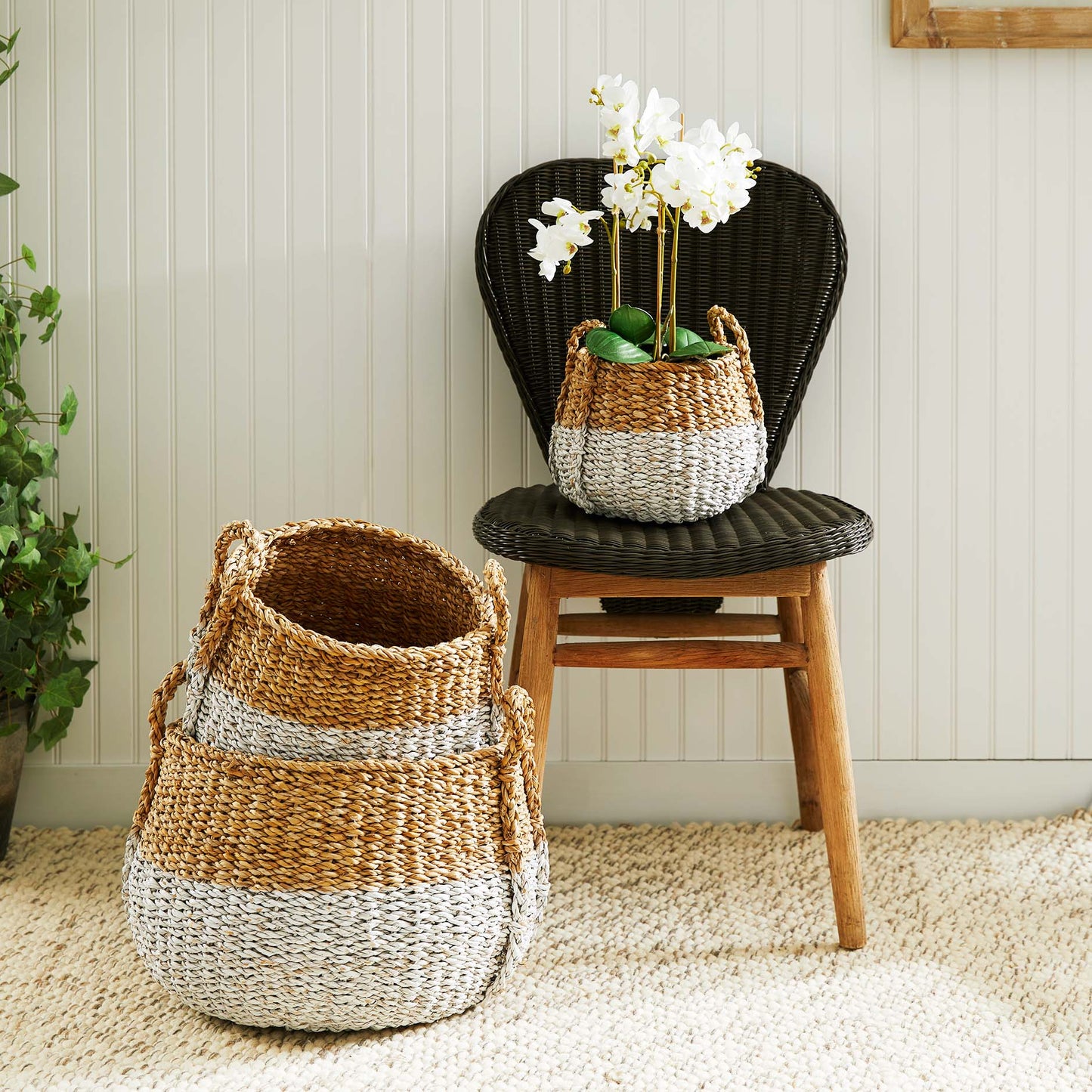 Woven two-tone seagrass baskets stylized with orchid and rug.