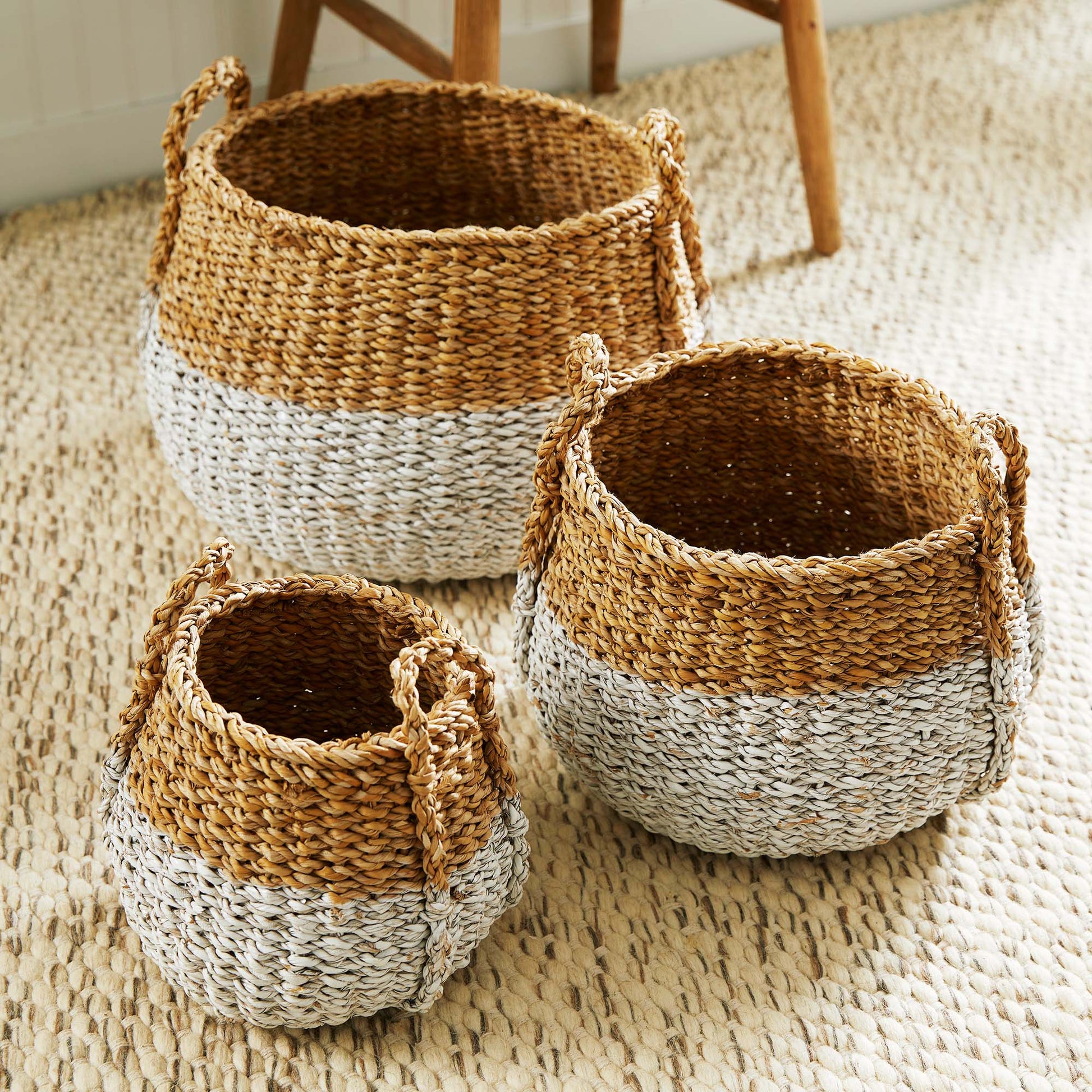 Woven two-tone seagrass baskets, top view, stylized on rug.